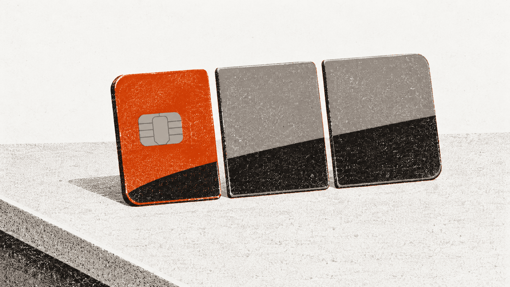 A bank card cut into three equal pieces arranged in a row on a plain counter, with the first piece set slightly ahead of the other two.