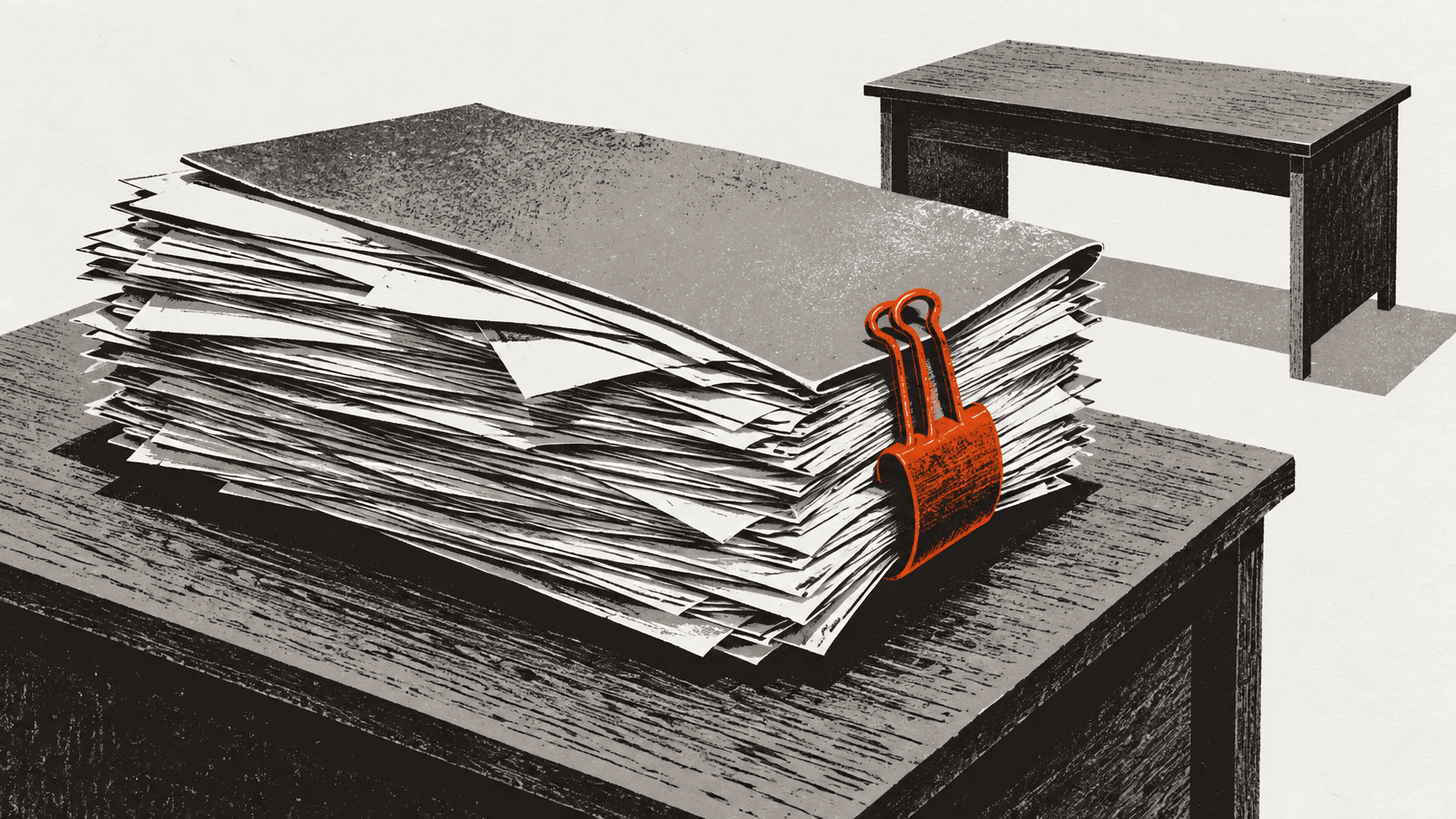 A bulging paper case file held together by one large bulldog clip on a desk, with a second, empty desk sitting just behind it.