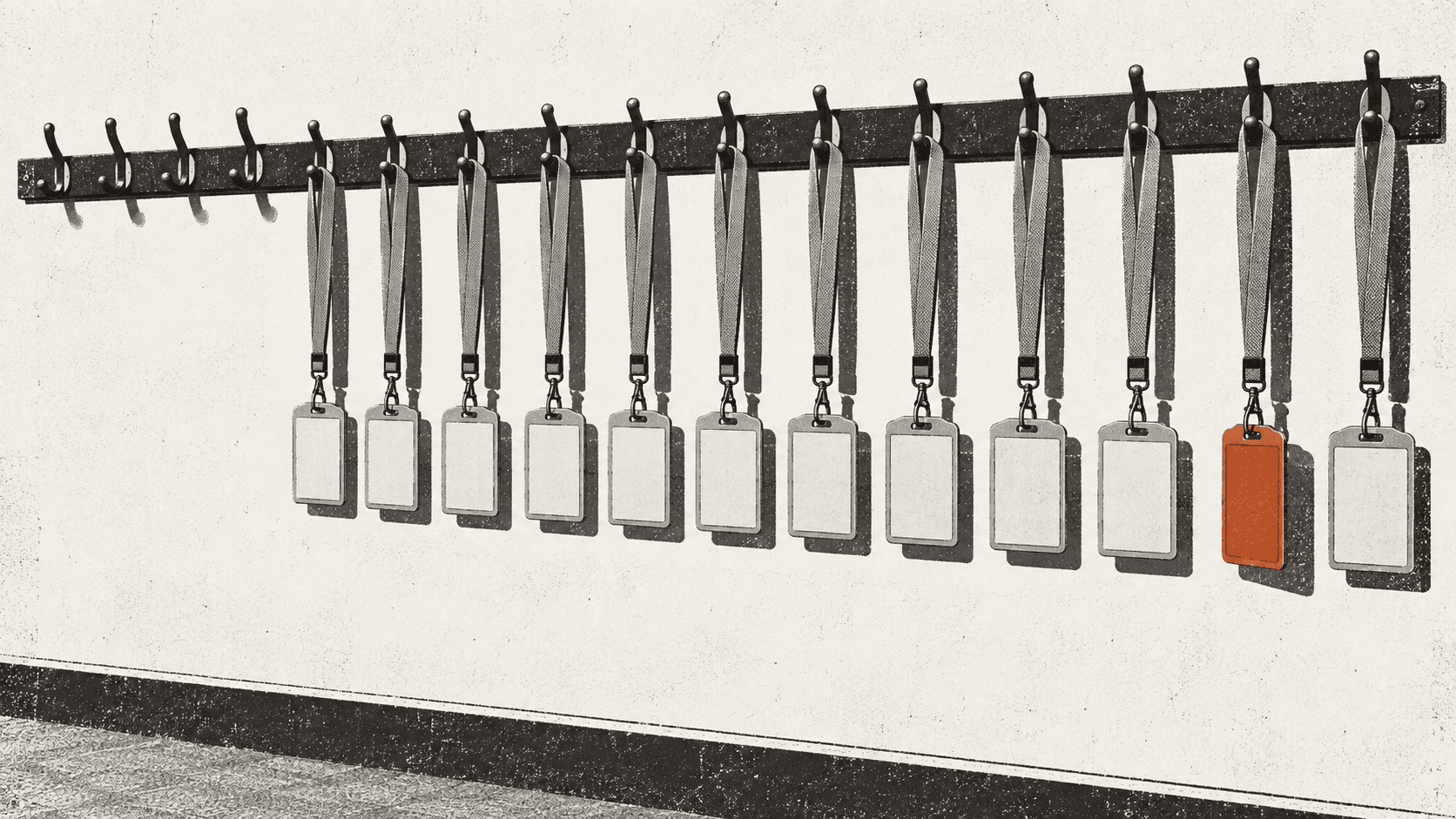 A wall of office coat hooks, most holding identical badges, with one cluster of hooks left completely bare and a single badge nearer the end turned face down so it cannot be read.